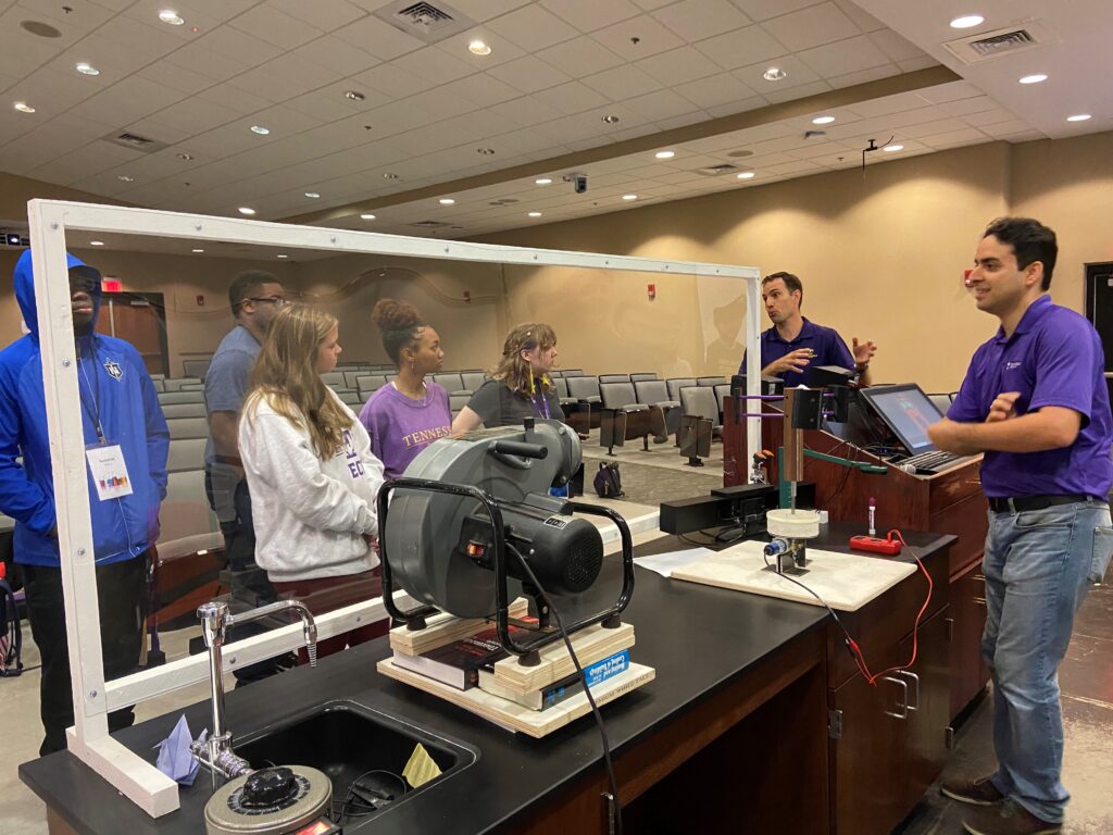 Dr. Vasel and Dr. Anton explaining a wind energy concept to a group of high school students